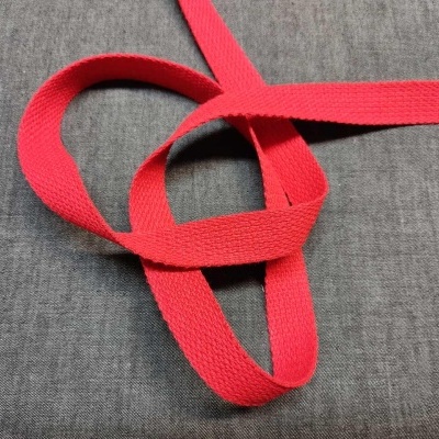 Tira vermelha de tecido entrelaçado sobre tecido cinzento liso