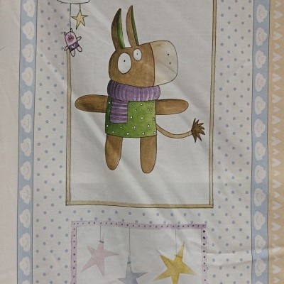 Colcha para berço com desenho de burro e estrelas em tons bege, azul e verde.