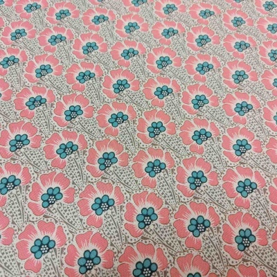 Tecido com padrão floral rosa e azul sobre fundo bege.