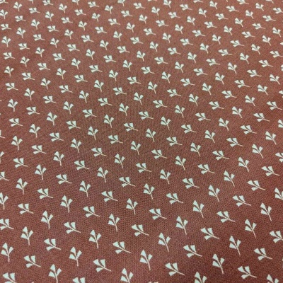 Tecido castanho com padrão de folhas brancas
