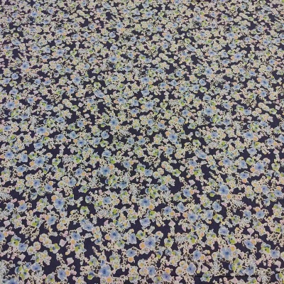 Tecido estampado floral azul, branco e verde sobre fundo preto