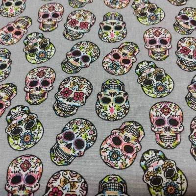 Tecido com padrão de caveiras coloridas sugar skull em fundo cinza