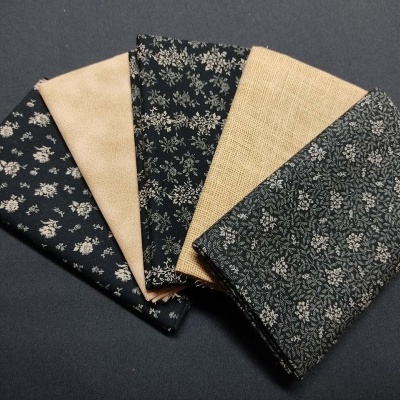 Tecidos dobrados com padrões florais e textura lisa em azul escuro e bege