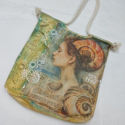 Saco de tecido com imagem artística de mulher e conchas marinhas em tons verdes e amarelos