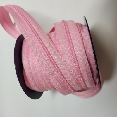 Rolo de fita cor-de-rosa enrolada num suporte preto