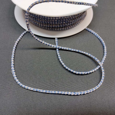 Carretel de cordão trançado azul claro, branco e cinza sobre superfície preta