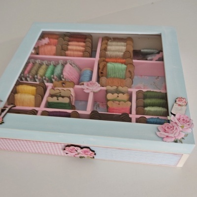 Caixa decorativa com carretéis de fios coloridos organizada em compartimentos