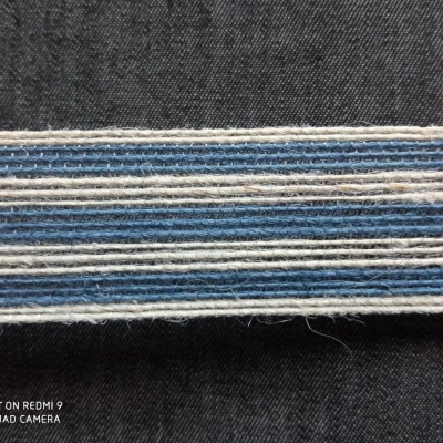 Faixa têxtil com linhas horizontais em azul claro, branco e azul escuro sobre tecido preto