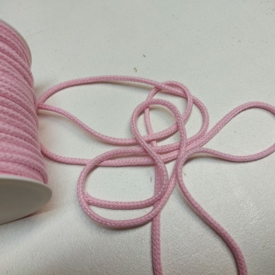 Rolo de cordão têxtil rosa com cordão parcialmente desenrolado