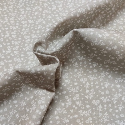 tecido bege com padrão de pequenas flores brancas