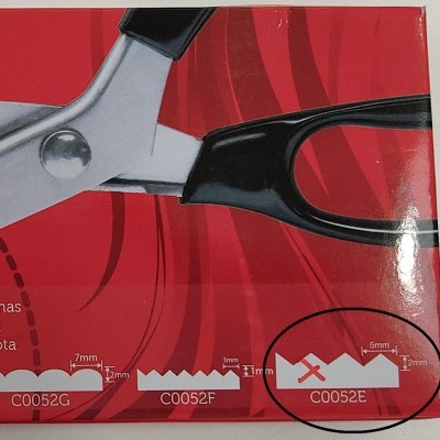 Detalhe de embalagem vermelha com ilustrações de tesouras e medidas técnicas.