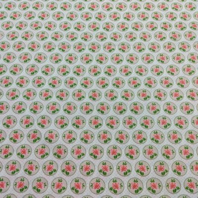 Tecido branco estampado com pequenos círculos contendo flores rosas e folhas verdes