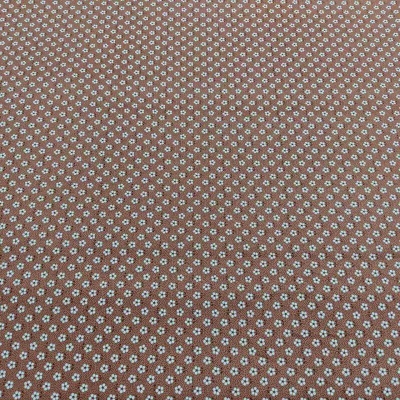 Pano castanho com padrão de pequenas flores brancas e azuis, textura lisa