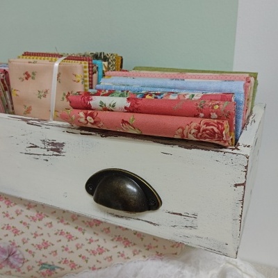 tecidos coloridos com padrões florais em caixa de madeira branca envelhecida