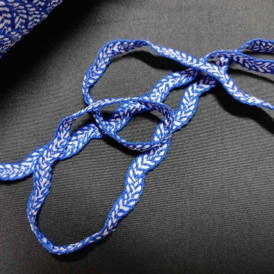 Cordão trançado azul e branco sobre tecido preto