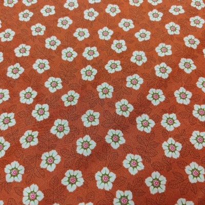 Tecido laranja com padrão repetido de flores brancas