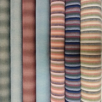 Rolos de tecidos com padrões xadrez, lisos e riscas horizontais