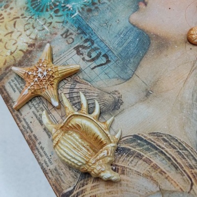 Arte decorativa com conchas marinhas e ilustração de mulher em tons dourados e azul