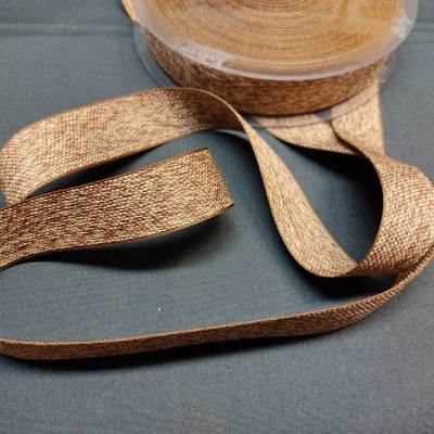 Rolo de fita decorativa castanha em tecido sobre superfície escura