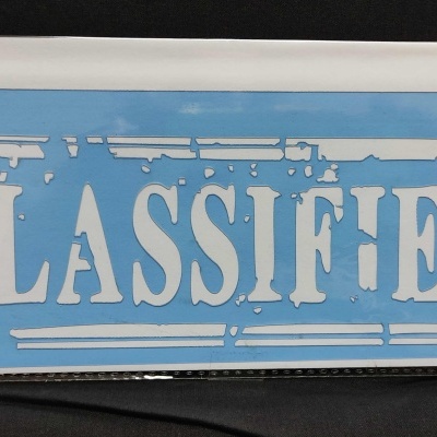 Placa decorativa azul com texto 'CLASSIFIED' branco desgastado