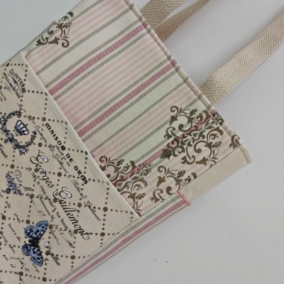 Mala de tecido bege com listras e padrões florais e texto em francês
