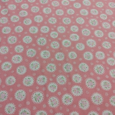 Tecido rosa com padrão floral em círculos brancos rendilhados