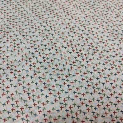 Tecido bege com padrão de pequenas cruzes coloridas