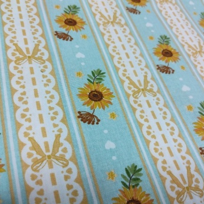 Tecido azul claro com padrões de girassóis, borboletas e listras brancas com detalhes dourados