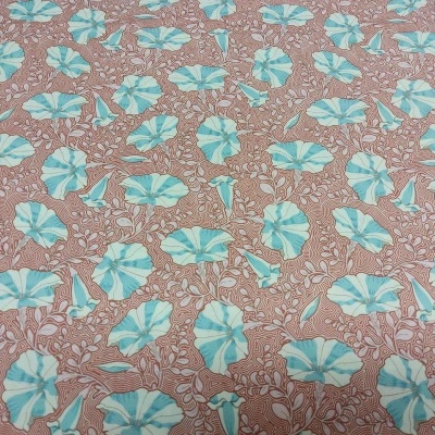 Tecido com padrão floral azul e branco sobre fundo bege e folhas marrons.