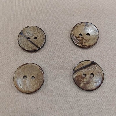 Quatro botões redondos em tons bege e castanho sobre tecido bege