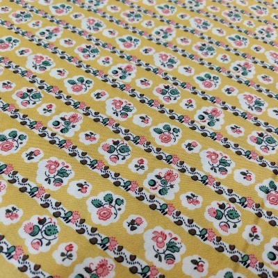 Tecido amarelo com padrão floral detalhado em rosa, branco e verde