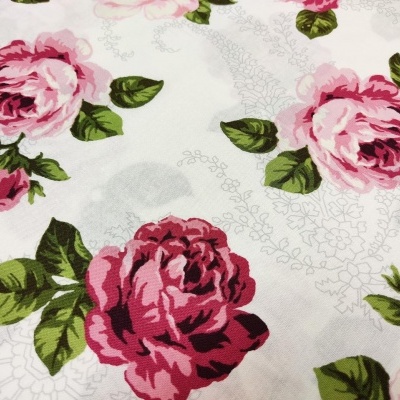 Tecido branco com padrão floral de rosas rosas e vermelhas com folhas verdes