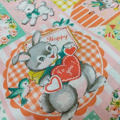 Tecido colorido com desenho de coelho cinzento, corações vermelhos e pássaros azuis