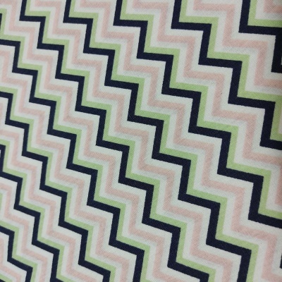 Tecido com padrão de linhas zigzag em verde, rosa, azul escuro e branco