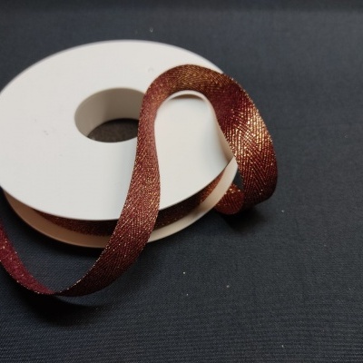 Fita castanho-metálica brilhante num carretel branco sobre fundo preto