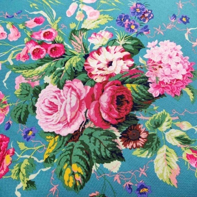 Tecido azul com flores rosas, vermelhas, lilases e folhas verdes em padrão floral