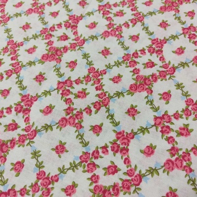 tecido branco com padrão floral rosa e folhas verdes, círculos azuis