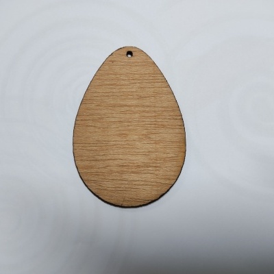 Pendente em forma de ovo de madeira clara com furo no topo sobre superfície branca
