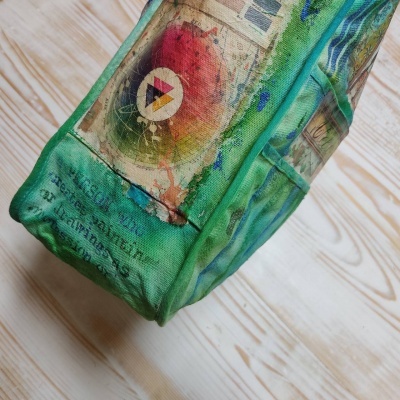 Mochila verde com padrão artístico colorido e texto em inglês