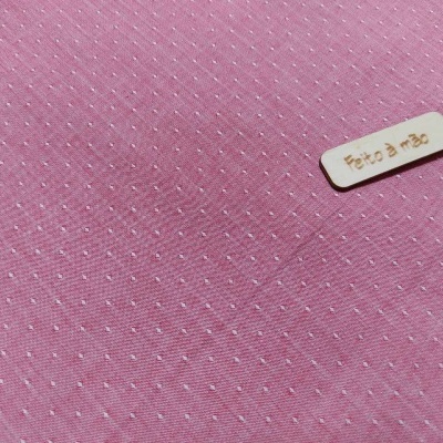 Tecido cor-de-rosa com pontos brancos e etiqueta 'Feito à mão'