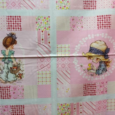 Tecido estampado com padrão patchwork e ilustrações de meninas em tons de rosa