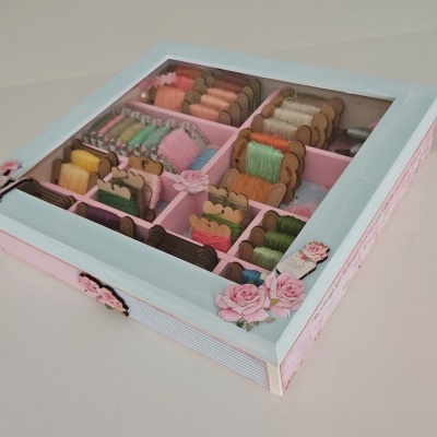 Caixa organizadora de madeira azul com tampa de vidro e carretéis de fios coloridos dentro