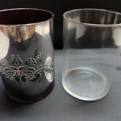 Dois copos, um de vidro transparente e um com suporte metálico decorado.