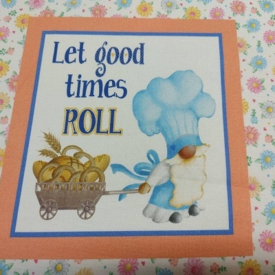 Tecido estampado com padrão floral e ilustração de cozinheiro com chapéu azul e carrinho de pães com texto em inglês