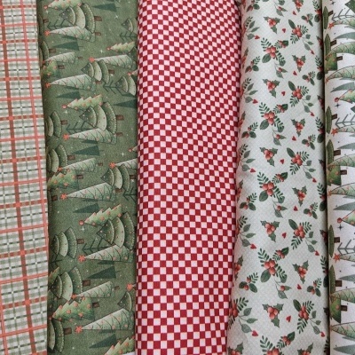 Rolos de tecido natalícios com padrões de pinheiros, quadrículas e bagas em verde, vermelho e branco
