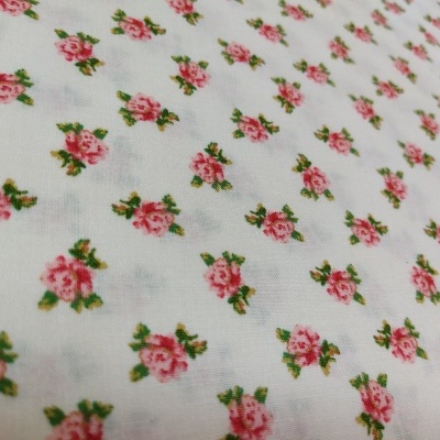 tecido branco com flores cor-de-rosa pequenas e folhas verdes