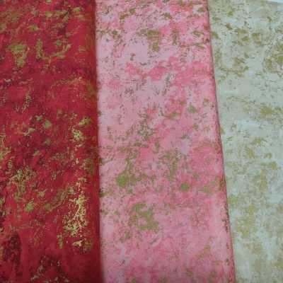 Tecidos vermelhos, rosa e branco com padrão marmorizado dourado