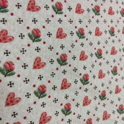 Tecido com padrão de corações cor-de-rosa, flores rosas e pequenos motivos florais pretos em fundo branco.