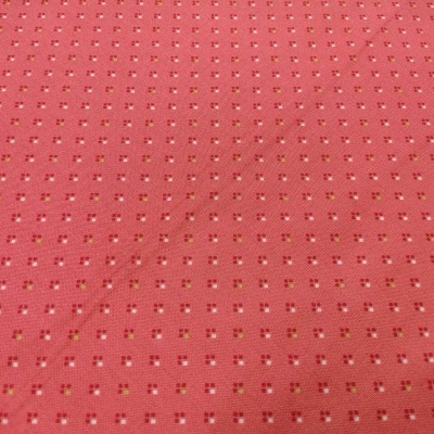 Tecido cor-de-rosa com padrão de pequenos quadrados brancos e vermelhos e manchas