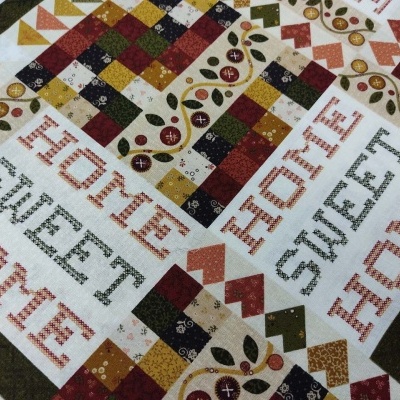 tecido estampado com padrão patchwork e texto bordado HOME SWEET HOME